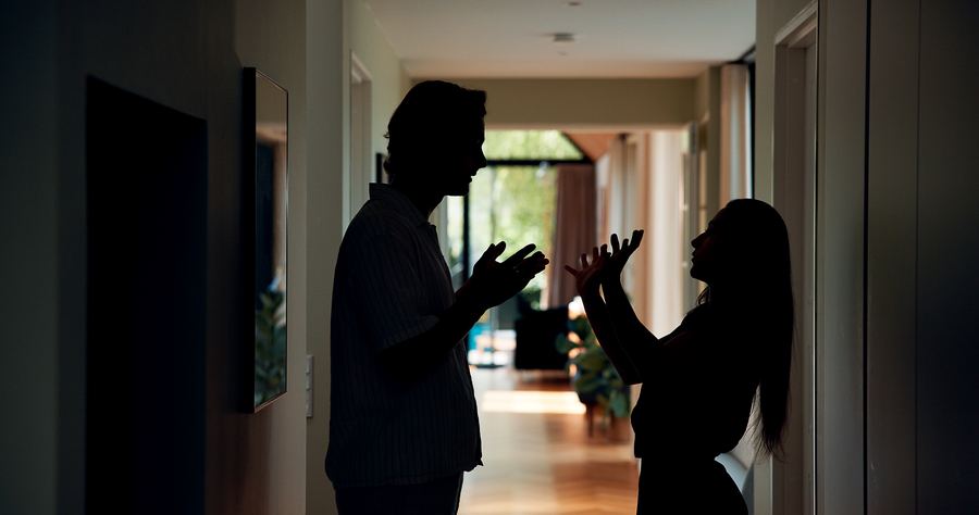 Two silhouettes mid-disagreement in a hallway — friction made visible.